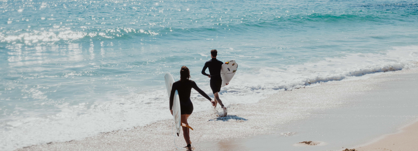 Surfers going into the water near MadFish Wines